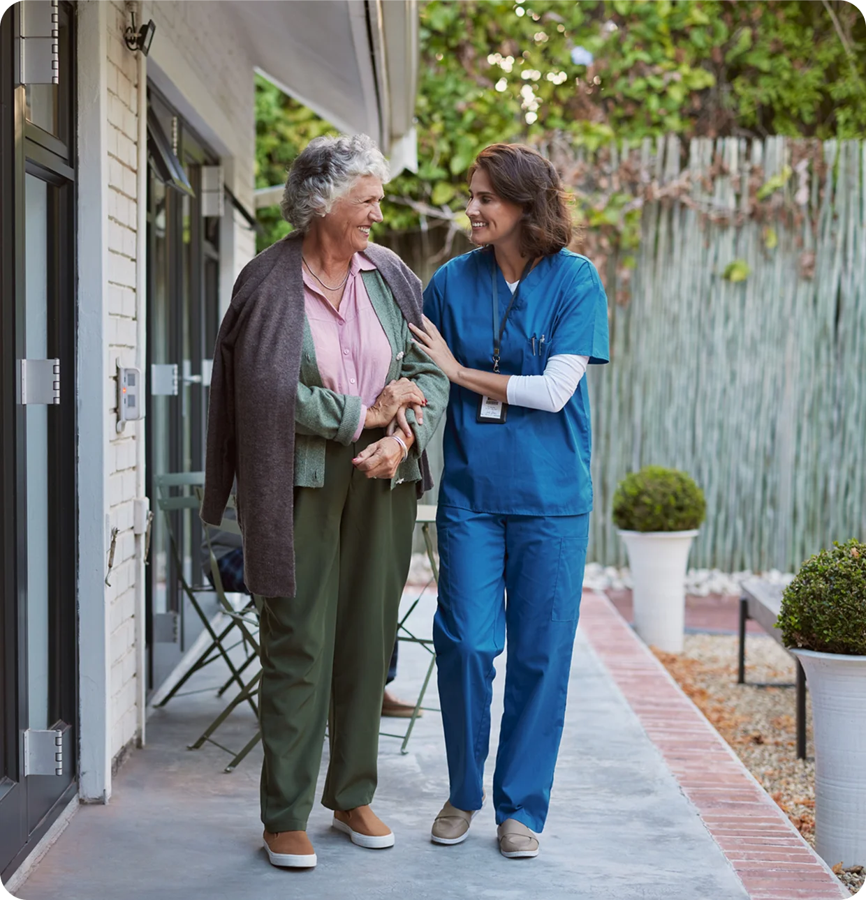 Elderly woman walking with nurse outside